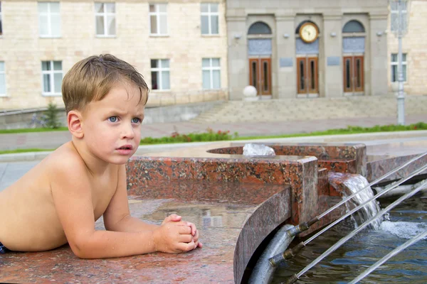 Boy near fountain in summer day — Stock Photo, Image