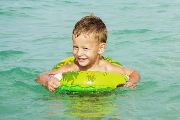 Niño feliz disfrutando nadando en el mar con anillo de goma — Foto de Stock