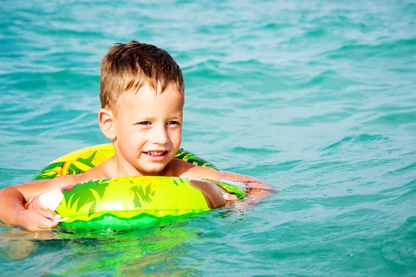 Menino feliz curtindo nadar no mar com anel de borracha — Fotografia de Stock