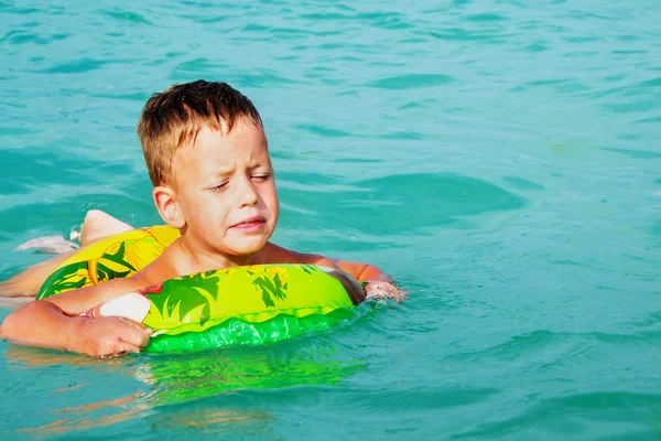 Menino feliz curtindo nadar no mar com anel de borracha — Fotografia de Stock