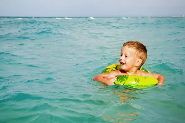 Niño feliz disfrutando nadando en el mar con anillo de goma —  Fotos de Stock