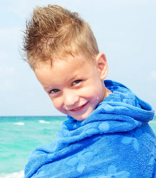 Liten pojke med en handduk på stranden — Stockfoto