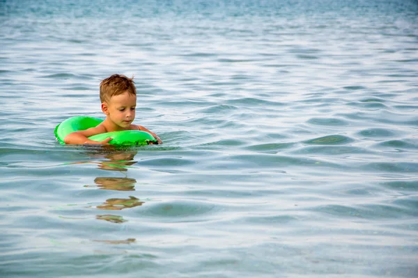 Lycklig pojke njuter av bad i havet med gummiring — Stockfoto