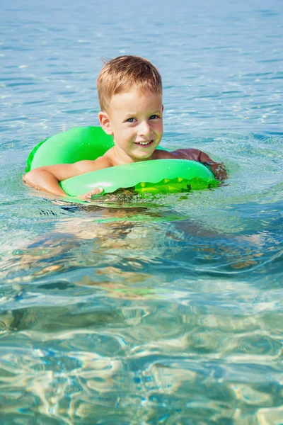 Niño feliz disfrutando nadando en el mar con anillo de goma — Foto de Stock