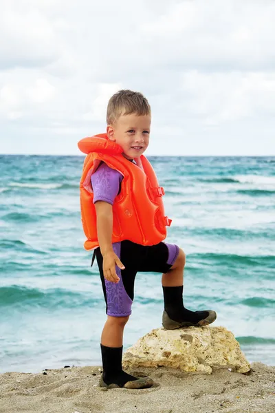 Petit garçon en combinaison de plongée et gilet de sauvetage à la plage — Photo