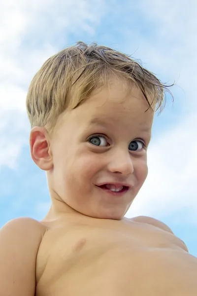Söt liten pojke mot blå himmel med vita moln — Stockfoto