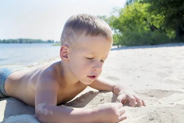 Young boy laying on sand beach — Stock Photo, Image