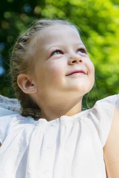 Portrait of a beautiful little girl in the forest. looking up — Stok fotoğraf