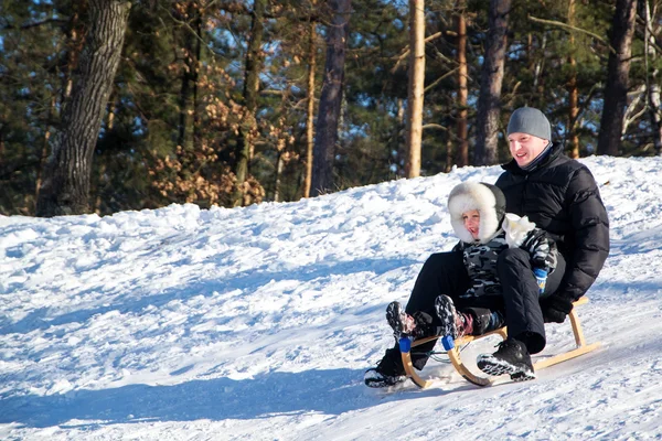 Vater und Sohn rutschen im Schnee. — Stockfoto