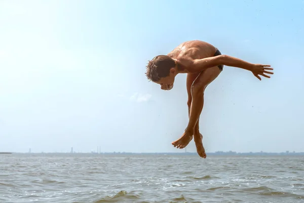Szczęśliwy dziesięcioletni chłopiec skaczący z powietrza do wody na szerokiej rzece. Summer wakacje zabawa koncepcja — Zdjęcie stockowe