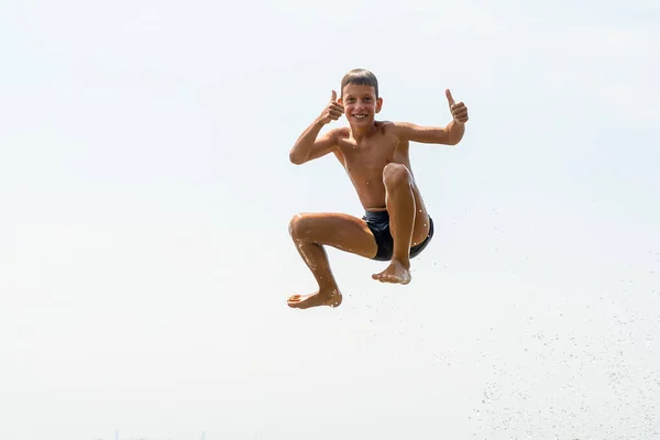 Fericit zece ani băiat sărind în apă pe râu larg din aer. Conceptul de vacanță de vară — Fotografie, imagine de stoc