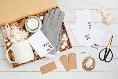 Bakım paketi, içinde kupa, mum, sıcak eldiven ve Noel süsü olan mevsimlik hediye kutusu. Kış tatili için kişisel çevre dostu sepet. Üst manzara, düz uzanma