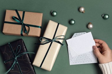 Yeşil zemin üzerinde hediye kutularıyla Noel arkaplanı. Xmas kutlaması, kış tatili hazırlıkları, gizli Noel Baba, takvim konsepti. Şenlikli maket, üst görünüm, düz yatış