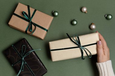 Yeşil zemin üzerinde hediye kutularıyla Noel arkaplanı. Xmas kutlaması, kış tatili hazırlıkları, gizli Noel Baba, takvim konsepti. Şenlikli maket, üst görünüm, düz yatış