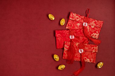 Çin Yeni Yıl Festivali dekorasyonu kırmızı arka planda. Geleneksel ay yeni yılı kırmızı cepleri, altın külçeleri servet, refah ve zenginlik anlamına gelir. Düz yatış, üst görünüm