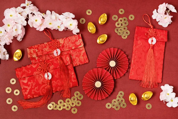 Çin Yeni Yıl Festivali dekorasyonu kırmızı arka planda. Geleneksel ay yeni yılı kırmızı cepleri, kağıt fanları, madeni paralar, altın külçeler, yazı anlamı servet, refah, zenginlik. Düz yatış, üst görünüm
