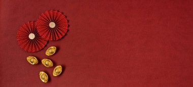 Çin Yeni Yıl Festivali dekorasyonu kırmızı arka planda. Geleneksel Ay 'ın yeni yıl kağıt hayranları ve altın külçeleri servet, refah ve zenginlik anlamına geliyor. Düz konum, üst görünüm, pankart