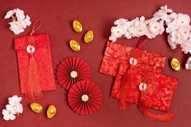 Çin Yeni Yıl Festivali dekorasyonu kırmızı arka planda. Geleneksel ay yeni yılı kırmızı cepleri, kağıt fanları, servet, zenginlik, servet anlamına gelen altın külçeler. Düz yatış, üst görünüm