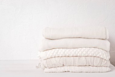 Soğuk hava için sıcak beyaz örgü giysiler yığını. Konforlu organik kazaklar. Hygge tarzı fikir