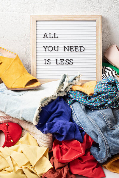 Быстрый модный фон с кучей дешевой, низкокачественной одежды. Одежда, сделанная в несправедливых, бесчеловечных условиях, идея. Воздействие на окружающую среду, концепция выбросов углерода