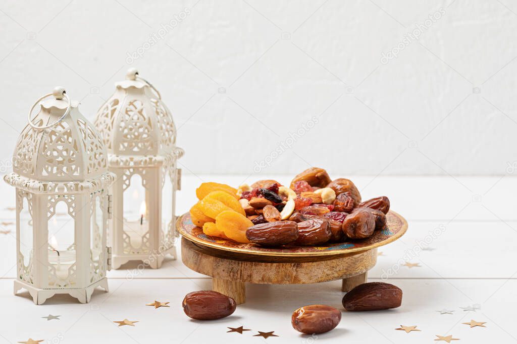 Ramadan Kareem and iftar muslim food, holiday concept. Trays with nuts and dried fruits and latterns with candles. Celebration idea