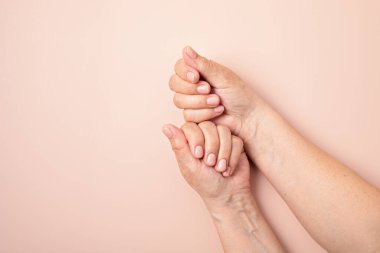 Çıplak manikürlü yaşlı bir kadının elleri. Açık pembe ojeli jöle. Güzellik, tedavi, kuaför konsepti. Tırnak tasarımı