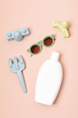 Çocuklar yaz aksesuarları ve güneşli günler ve tatiller için güneş kremi şişesi. Güneş gözlükleri, sandaletler, kumsal eğlencesi için kum kalıpları. 