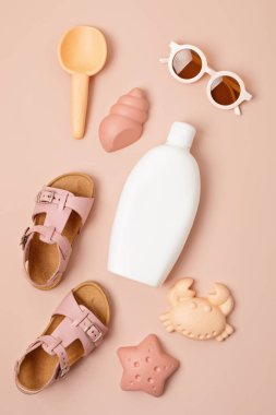 Çocuklar yaz aksesuarları ve güneşli günler ve tatiller için güneş kremi şişesi. Güneş gözlükleri, sandaletler, kumsal eğlencesi için kum kalıpları.