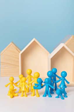 Sığınak arayan Ukraynalı aileler kavramı. Ahşap evlerin önündeki sarı ve mavi bebekler. Güvenli bir yer arayan savaş terörü mağdurları. Sivillerin ve Ukraynalı ailelerin tahliyesi