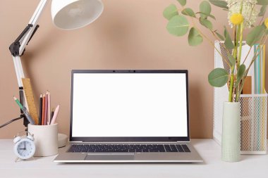 Empty laptop screen, desktop organizer with desk lamp and office supplies. Back to school, home office, begining of studies concept. Mockup, template