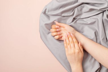 Çıplak manikürlü, temiz tenli genç bir kadının elleri. Açık pembe ojeli jöle. Güzellik, tedavi, kuaför konsepti. Tırnak tasarımı