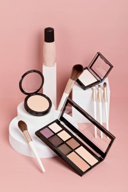 Makyaj ürünleri beyaz podyumlarda pembe renkli arka planda sergileniyordu. Markalaşma ve paketleme sunumu için model