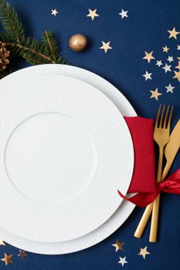 Altın çatal bıçak, porselen tabak ve noel süslemeleri ile birlikte Noel sofrası. Yer kartı maketi, yemek davetiyesi, restoran menü şablonu. Boşluğu kopyala