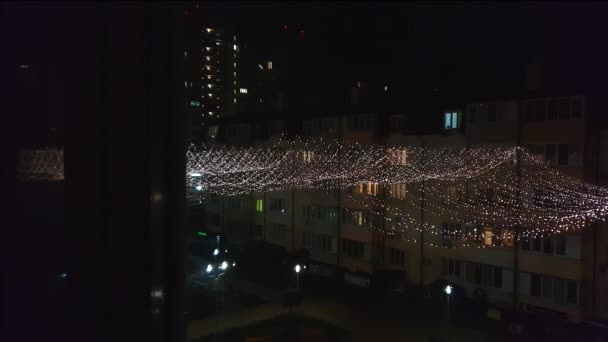 Zicht vanuit het raam op een miljoen lichtjes van een vakantiebloemenslinger in de grote stad — Stockvideo