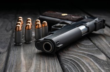 Ahşap arka planda tabanca ve fişekler var. Nefsi müdafaa için kısa namlulu bir silah..