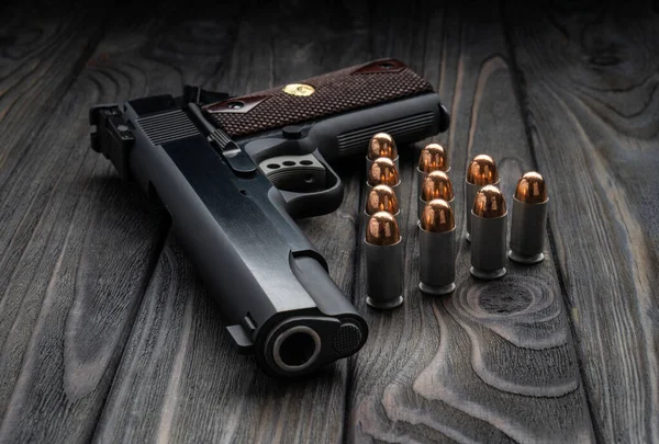 Ahşap arka planda tabanca ve fişekler var. Nefsi müdafaa için kısa namlulu bir silah..