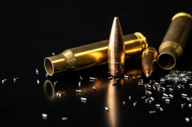 Parçalanmış tüfek fişeklerinin yakın çekimi. Kurşun, refleksle siyah arka planda izole edilmiş. Siyah üzerine karabina mermisi. Granüle edilmiş barut..