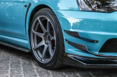 Spor bir arabanın tekerini kapat. Düşük profilli lastikli gri araba jantı. Mavi spor araba.