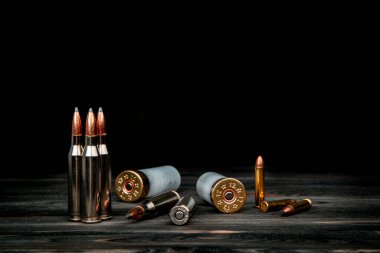 Ahşap bir yüzeyde çeşitli mühimmat çeşitleri. Silahlar için fişekler. Koyu arkaplan.
