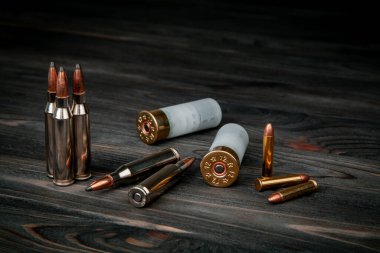 Ahşap bir yüzeyde çeşitli mühimmat çeşitleri. Silahlar için fişekler. Koyu arkaplan.