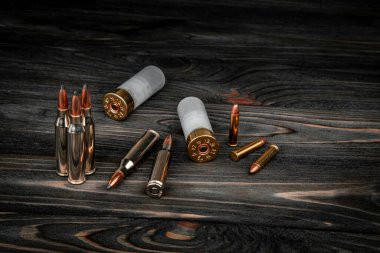 Ahşap bir yüzeyde çeşitli mühimmat çeşitleri. Silahlar için fişekler. Koyu arkaplan.