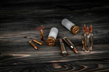 Ahşap bir yüzeyde çeşitli mühimmat çeşitleri. Silahlar için fişekler. Koyu arkaplan.
