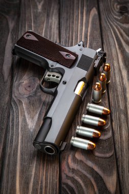 Ahşap bir arka planda modern siyah silah ve mühimmat. Tabanca. Spor ve nefsi müdafaa için silahlar masanın üzerinde..