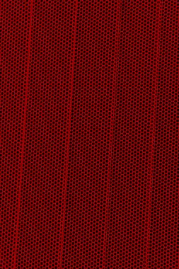 Dalgalı metalik delikleri olan kırmızı zemin. Arka plan olarak metal ağ. Delinmiş metal geri geldi.. 