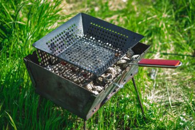 Sıcak kömürlü barbekü ve kızarmış et için boş bir ağ. Doğada piknik. Mayıs tatilleri. Açık yeşil arkaplan.
