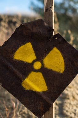 Paslı metal bir plakada radyasyon işareti. Tehlike uyarısı. Kıyamet sonrası işareti..