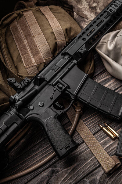 Современный автоматический карабин и картриджи для него на деревянном фоне. Крупный план оружия на тёмном фоне
.