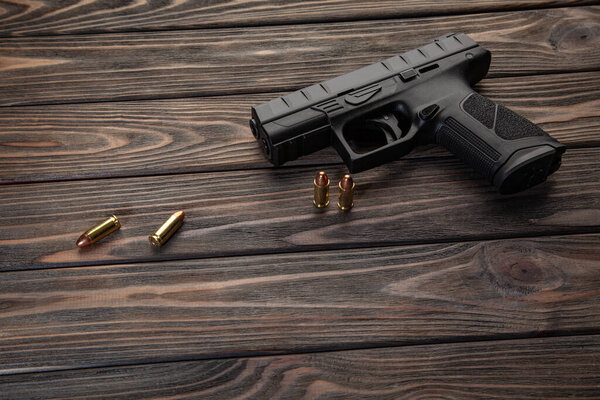 Pistol and cartridges for it on a wooden background. A short-barreled weapon for self-defense.