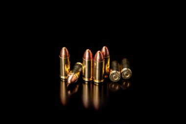 Pistol fişekleri 9 mm 'lik pürüzsüz, parlak bir yüzeyde yansımaları var. Koyu arkaplanda tabancalar ve PCC karabinalar için mühimmat.