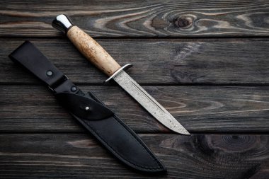 Tahta saplı ve siyah deri kılıflı av bıçağı. Şam çelik bıçağı. Tahtalardan klasik ahşap arkaplan.